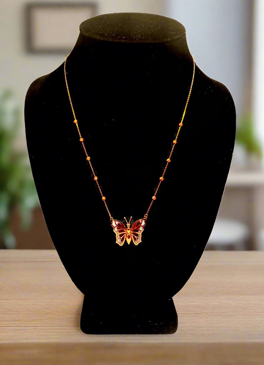 Butterfly necklace on a black mannequin bust against a white background