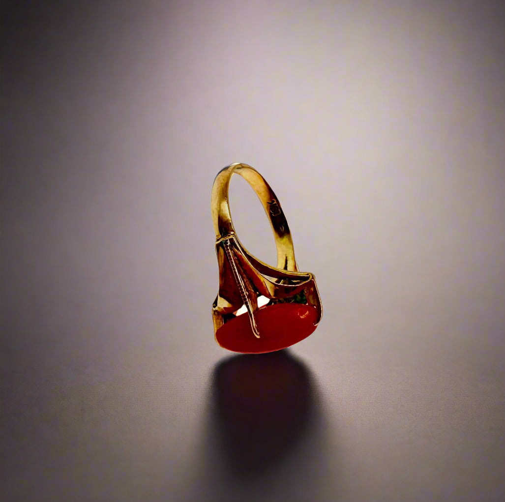 Gold ring with a red stone on a light gray background