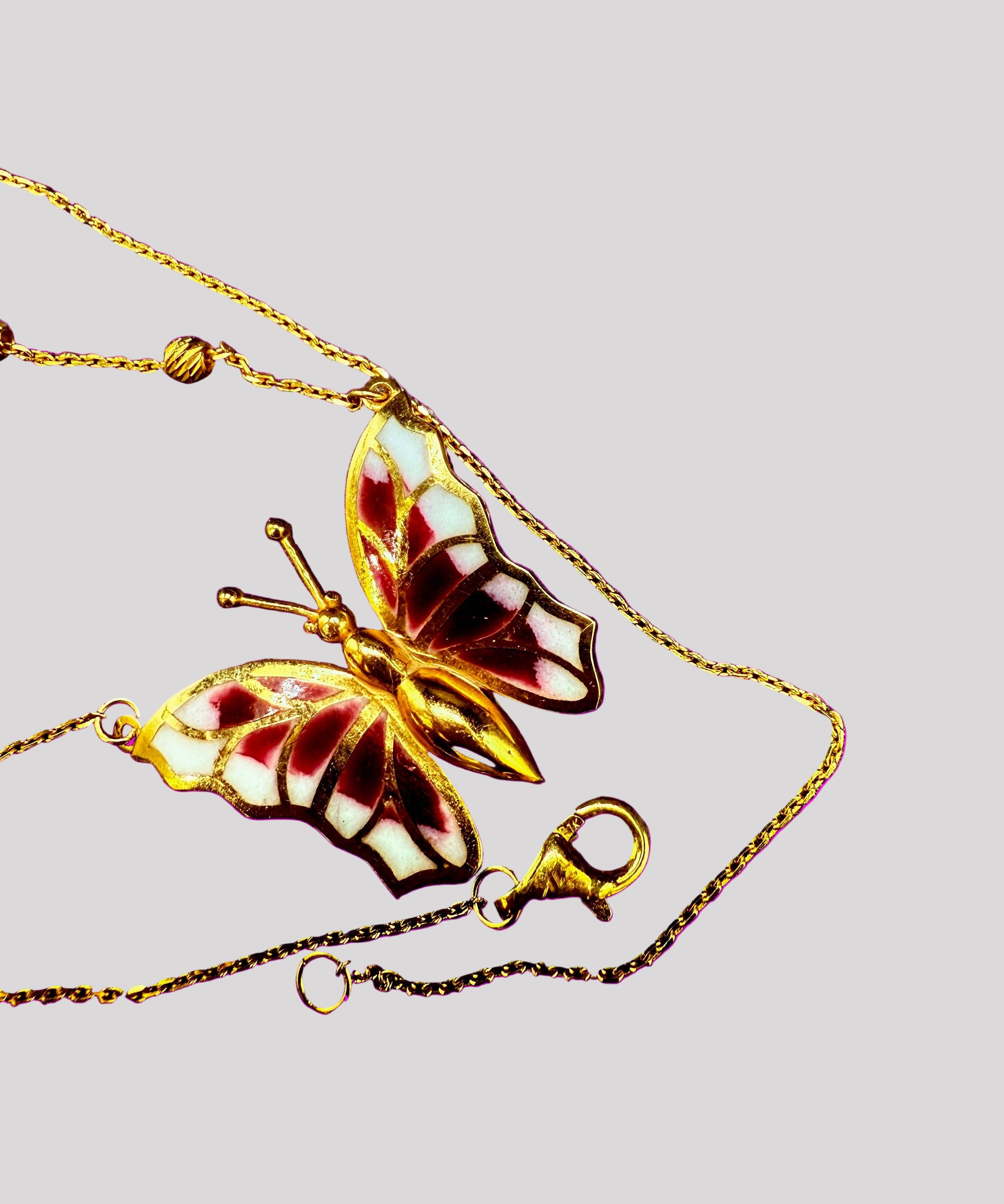 Butterfly-shaped pendant on a gold chain against a dark background