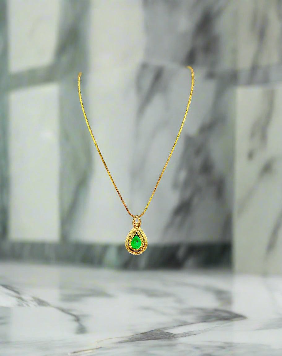 Gold necklace with a green pendant on a black velvet stand against a dark background