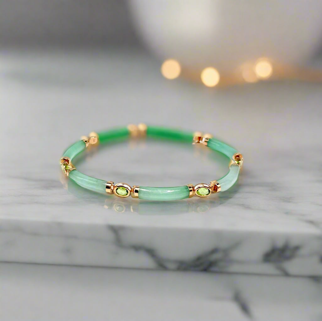 Green bracelet with gold accents on a light gray background